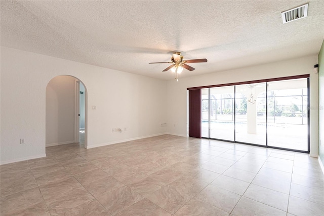 spare room with arched walkways, ceiling fan, a textured ceiling, and visible vents