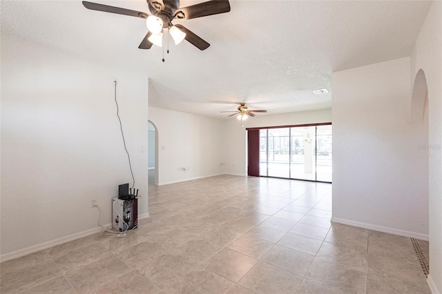 unfurnished room featuring arched walkways, visible vents, ceiling fan, a textured ceiling, and baseboards