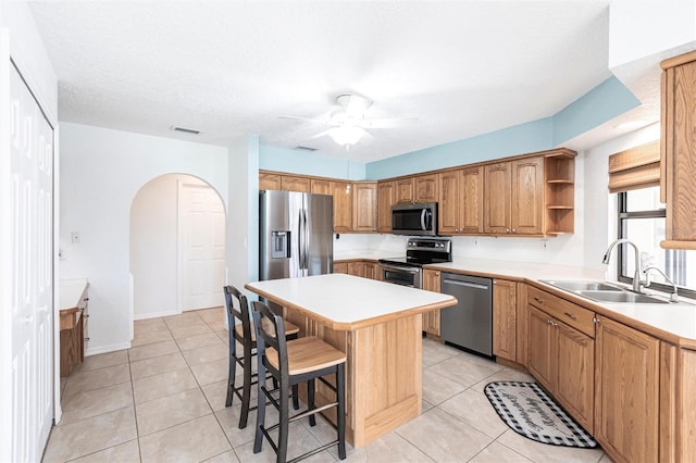 kitchen featuring light countertops, appliances with stainless steel finishes, a sink, and a center island