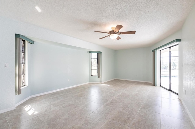 empty room with ceiling fan, baseboards, and a textured ceiling