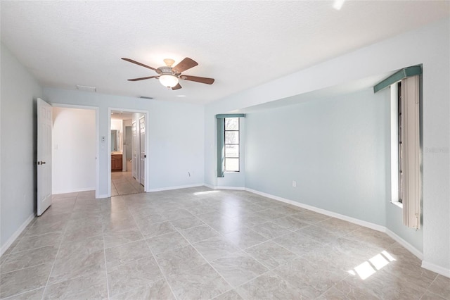 empty room featuring a textured ceiling, baseboards, visible vents, and a ceiling fan