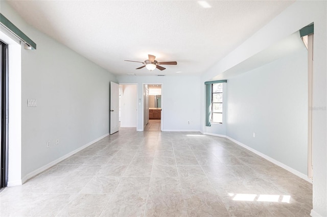 unfurnished room featuring a textured ceiling, ceiling fan, light tile patterned floors, and baseboards