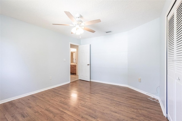 unfurnished bedroom with baseboards, a ceiling fan, dark wood-type flooring, a textured ceiling, and a closet