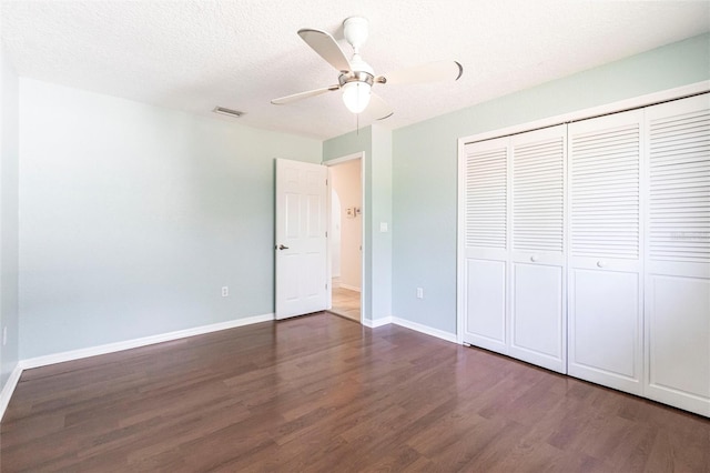 unfurnished bedroom featuring visible vents, baseboards, dark wood finished floors, a textured ceiling, and a closet