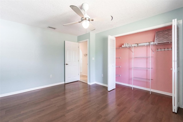 unfurnished bedroom with dark wood-style flooring, a closet, visible vents, a textured ceiling, and baseboards