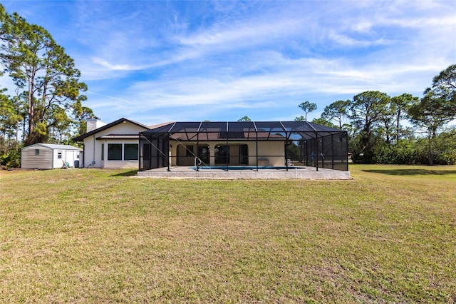 rear view of property featuring glass enclosure, an outdoor structure, a lawn, a storage unit, and a chimney