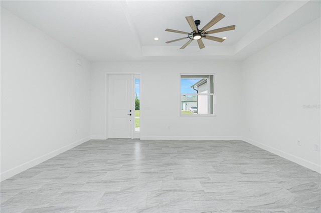 spare room with a tray ceiling, recessed lighting, a ceiling fan, and baseboards