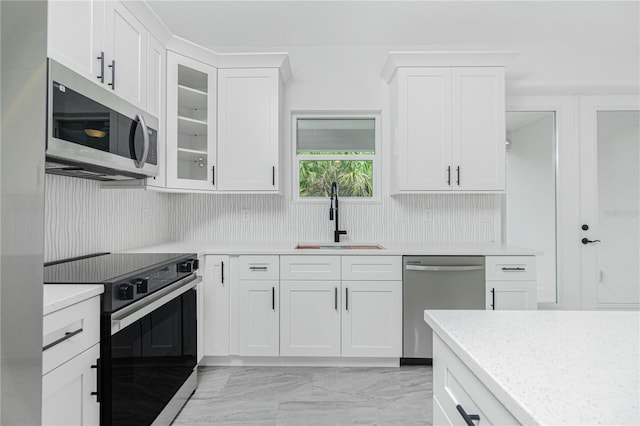 kitchen featuring a sink, white cabinetry, marble finish floor, appliances with stainless steel finishes, and glass insert cabinets