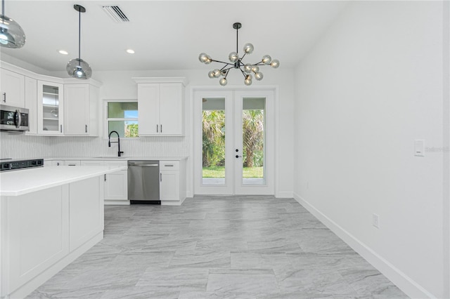 kitchen featuring light countertops, appliances with stainless steel finishes, glass insert cabinets, white cabinetry, and a sink