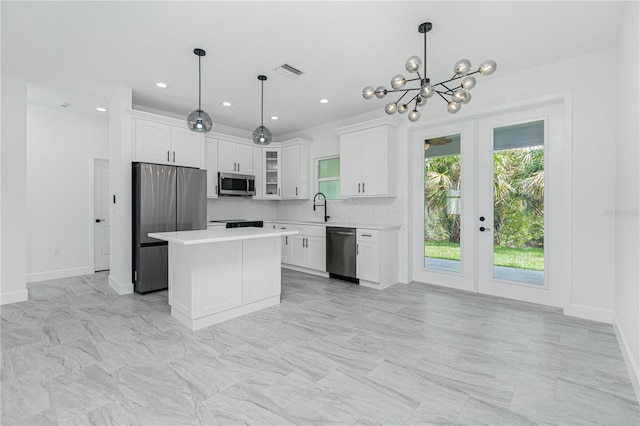 kitchen with appliances with stainless steel finishes, a center island, light countertops, and glass insert cabinets