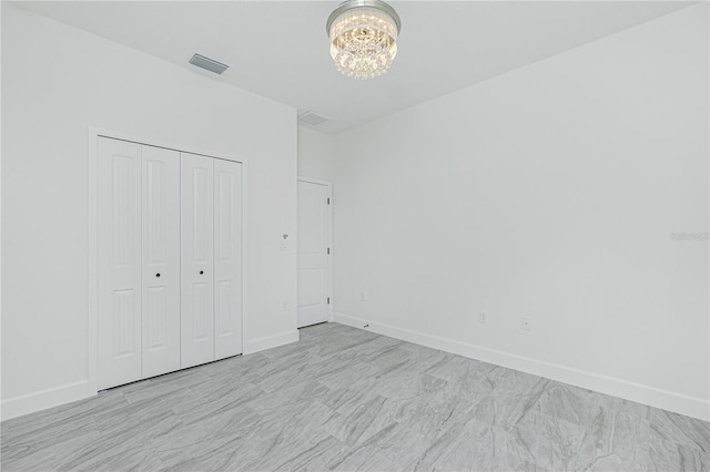 unfurnished bedroom with baseboards, visible vents, a chandelier, and a closet