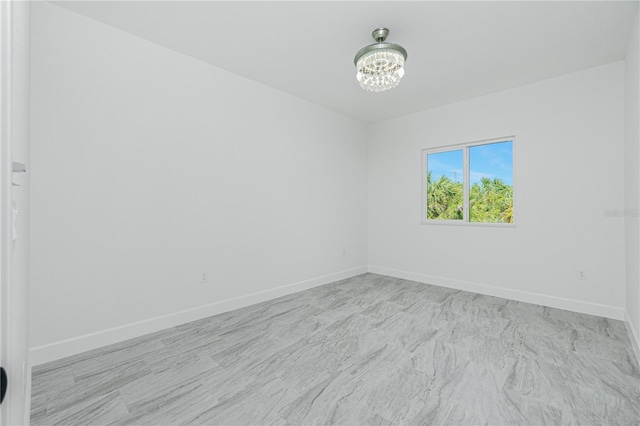 empty room with baseboards and a chandelier