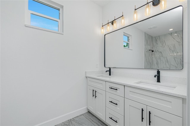 full bath featuring double vanity, marble finish floor, baseboards, and a sink