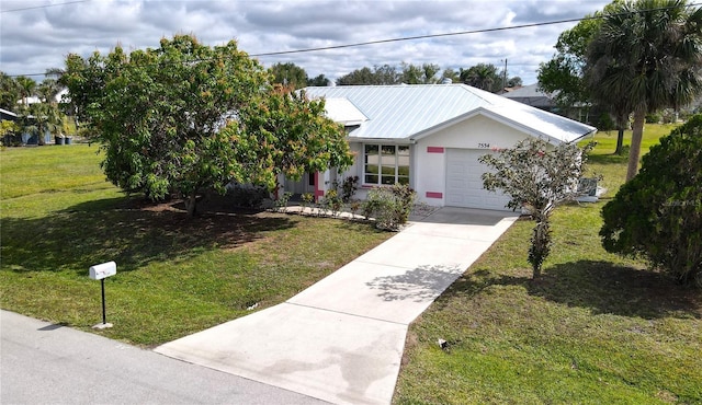 view of front of home with metal roof, an attached garage, driveway, stucco siding, and a front lawn