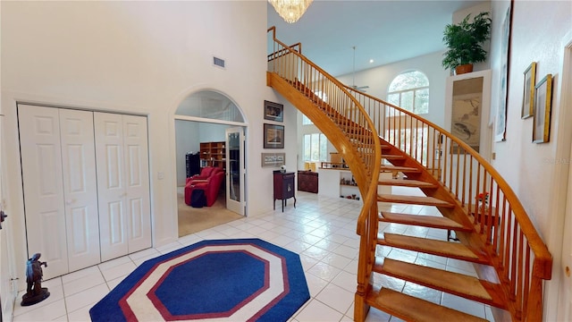 stairway with a towering ceiling, tile patterned flooring, and visible vents