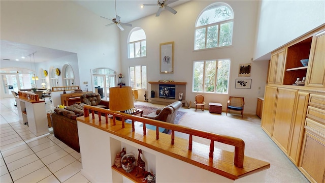 living area featuring a glass covered fireplace, light tile patterned flooring, ceiling fan, and light carpet