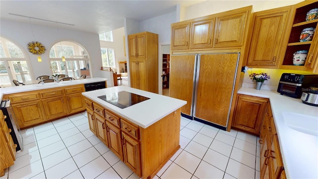 kitchen with brown cabinets, light countertops, a kitchen island, and black appliances