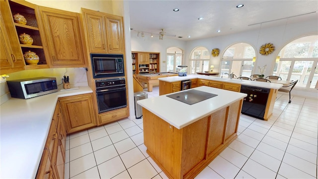 kitchen with a kitchen island, a peninsula, light countertops, black appliances, and light tile patterned flooring