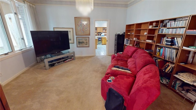 living room with crown molding, baseboards, and light colored carpet