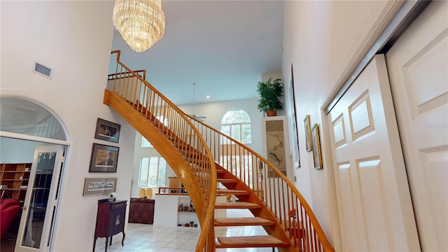 staircase featuring a high ceiling, visible vents, and a notable chandelier