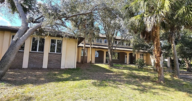 view of front of home featuring brick siding, a front yard, and stucco siding