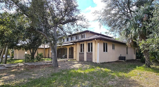 view of side of property featuring a yard, cooling unit, and stucco siding