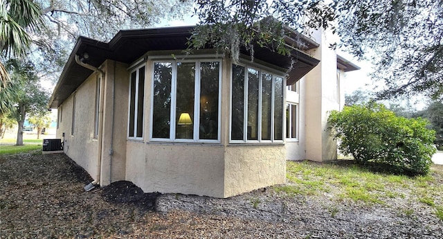 view of side of property featuring cooling unit and stucco siding