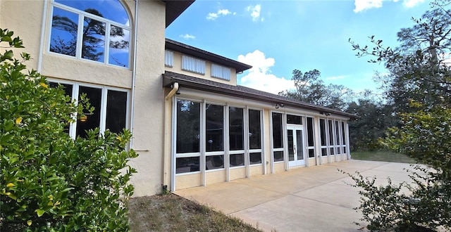 rear view of house featuring a patio area and stucco siding