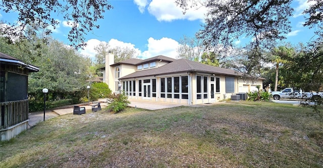 view of side of home featuring a lawn, a sunroom, a chimney, central air condition unit, and a patio area