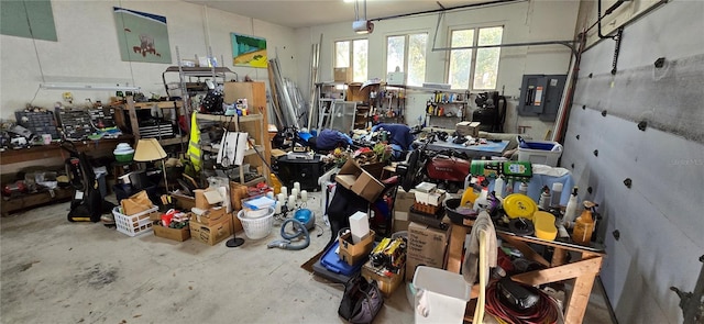 miscellaneous room with a garage, a workshop area, unfinished concrete flooring, and electric panel