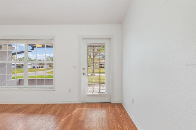 doorway with baseboards and light wood-style floors