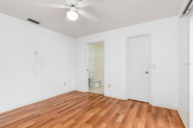 unfurnished bedroom featuring visible vents, ensuite bathroom, a ceiling fan, light wood-style floors, and baseboards