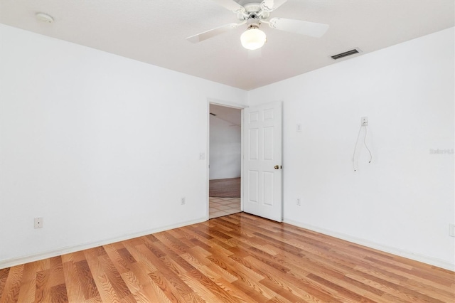 spare room with visible vents, baseboards, light wood-type flooring, and a ceiling fan