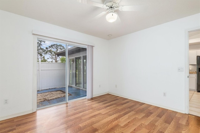 empty room with light wood finished floors, baseboards, and a ceiling fan