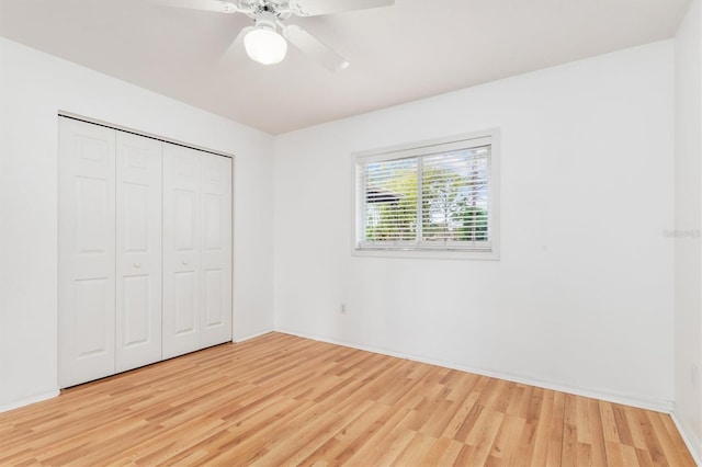 unfurnished bedroom featuring a closet, baseboards, light wood-style floors, and ceiling fan