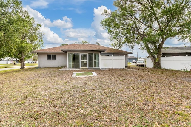 back of property featuring stucco siding, a sunroom, and fence