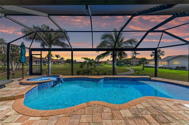 pool at dusk with glass enclosure, a pool with connected hot tub, and a patio