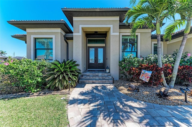 property entrance featuring french doors, a tile roof, and stucco siding