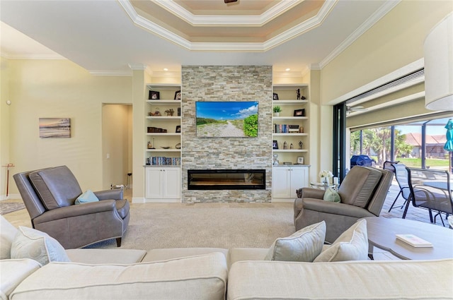 carpeted living room featuring ornamental molding, a stone fireplace, a raised ceiling, and built in features