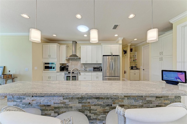 kitchen with crown molding, tasteful backsplash, visible vents, appliances with stainless steel finishes, and wall chimney range hood