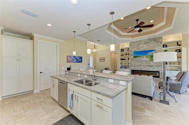 kitchen with a stone fireplace, a sink, built in features, open floor plan, and dishwasher