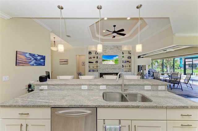 kitchen with built in features, a tray ceiling, ornamental molding, open floor plan, and a sink