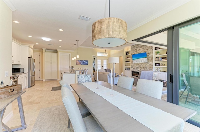 dining space featuring built in shelves, recessed lighting, a large fireplace, visible vents, and ornamental molding