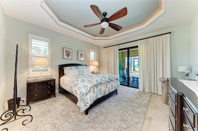 bedroom featuring access to outside, multiple windows, and a raised ceiling