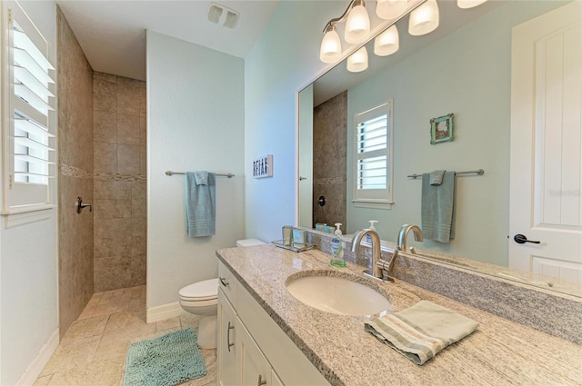 full bathroom featuring visible vents, toilet, vanity, tiled shower, and baseboards