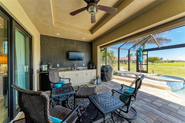 view of patio featuring a ceiling fan, area for grilling, an in ground hot tub, a lanai, and a sink