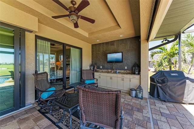 view of patio with ceiling fan, a sink, and a grill