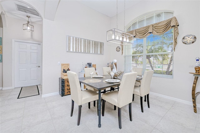 dining space with arched walkways, light tile patterned floors, visible vents, a high ceiling, and baseboards