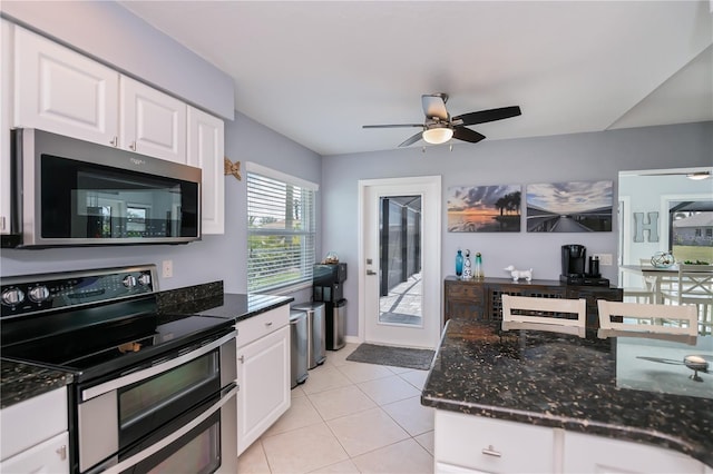 129 Barre Dr NW, Port Charlotte, FL 33952 - kitchen with light tile patterned floors, ceiling fan, stainless steel appliances, white cabinets, and dark stone countertops
