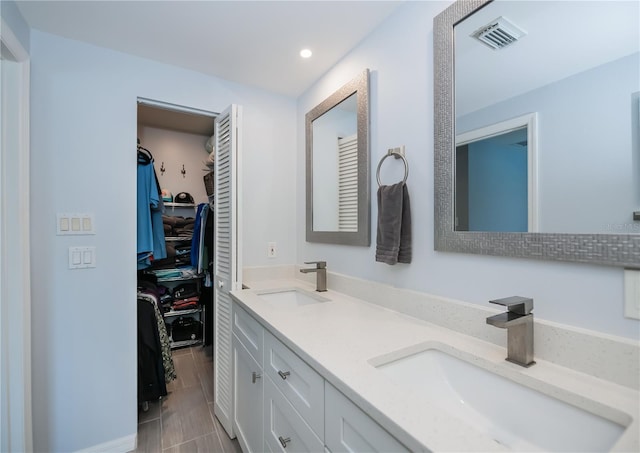 129 Barre Dr NW, Port Charlotte, FL 33952 - bathroom featuring a walk in closet, visible vents, a sink, and double vanity